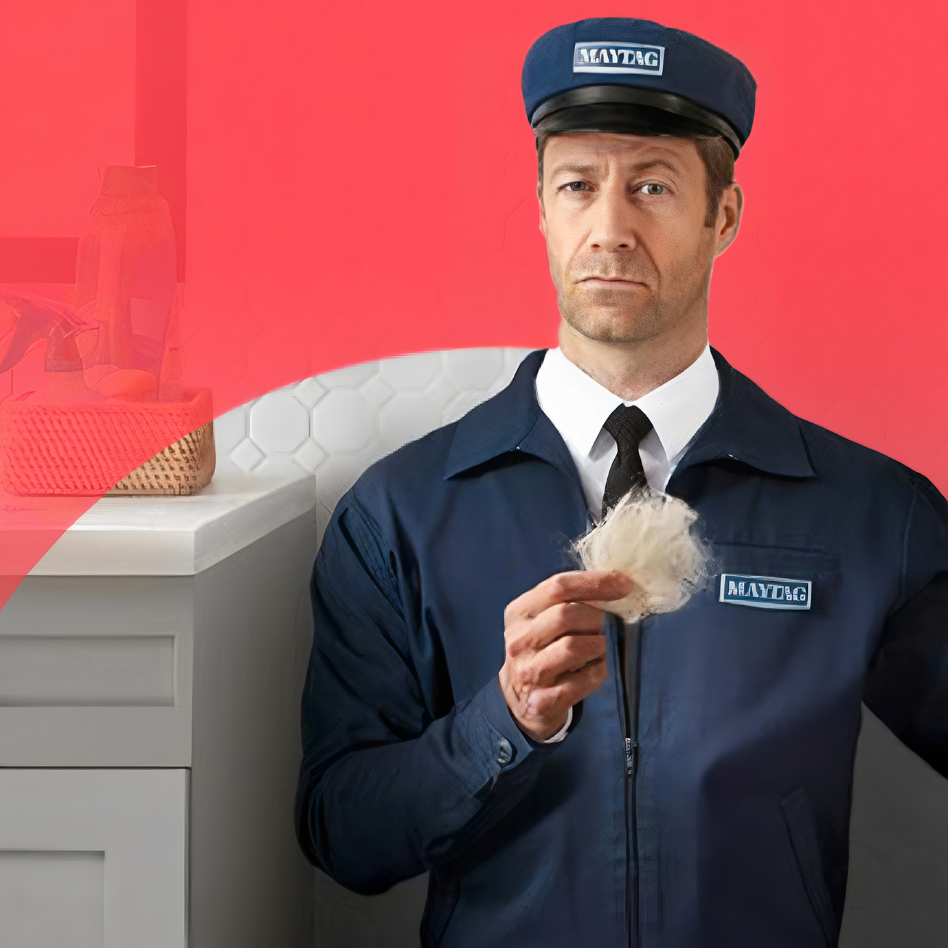 A man in a kitchen with a solemn expression holds up a handful of pet hair.