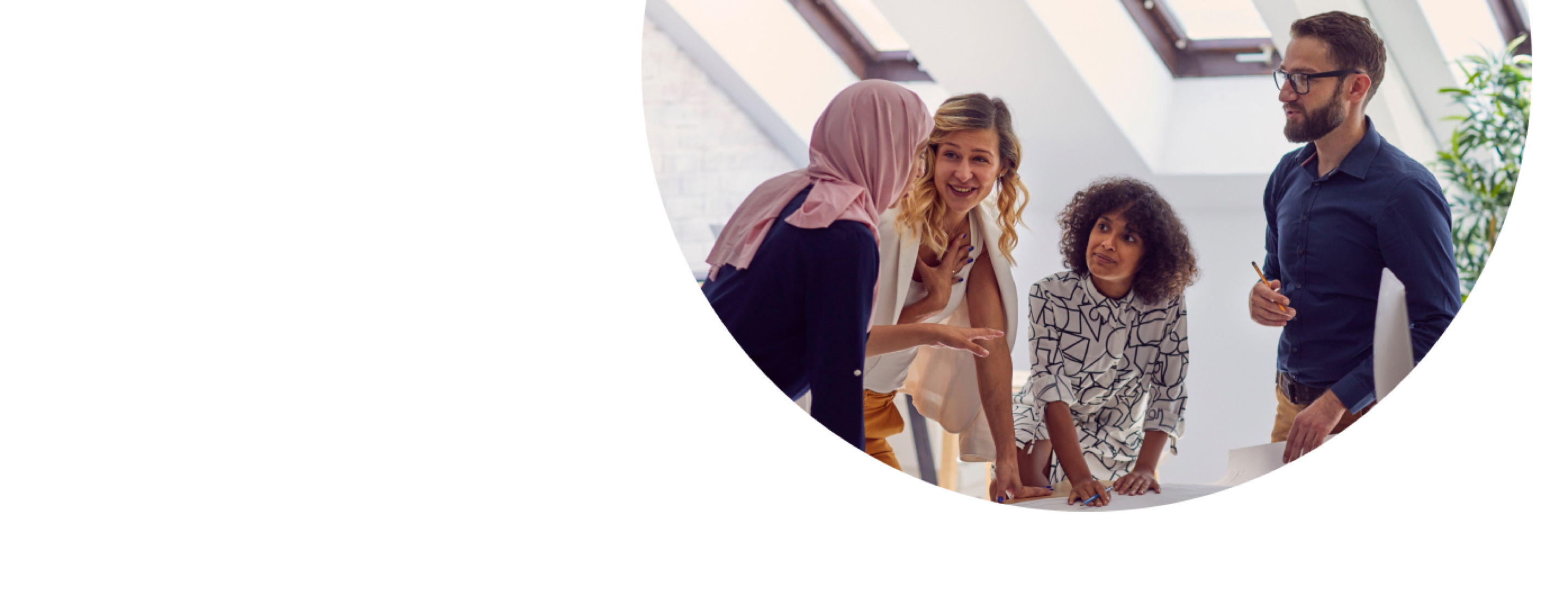 A group of young employees chat in an office setting.